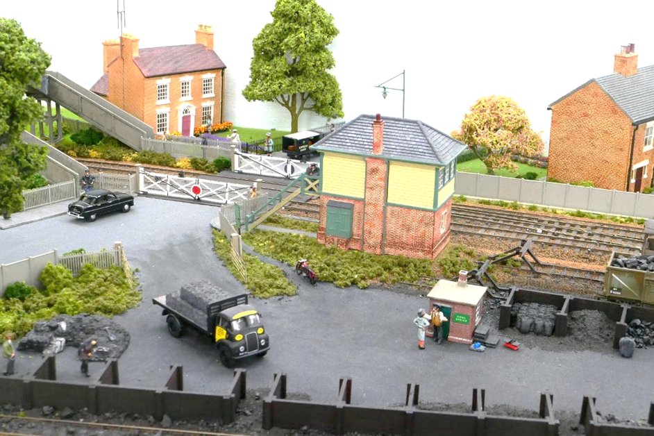 Ewhurst Green’s Horsham Lane level crossing.
In the foreground a lady is remonstrating with the coal merchant while the signalman looks down at the commotion. A Ford Consul waits at the gates. 
www.EwhurstGreen.com 
