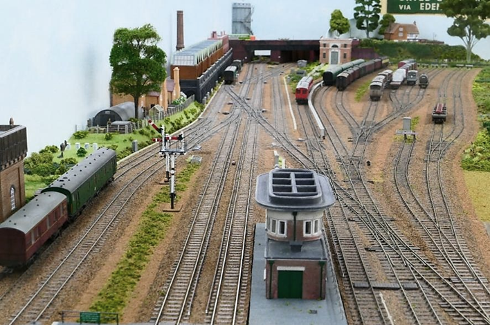 Looking south towards the double junction and the line to Cranleigh (curves away just to the left of and behind the sub-station) from above the Up Main Line platform. 
The correct six-foot dimension between Up and Down Main lines is noticeable in this photograph as is the correct conductor rail offset whilst allowing for the 16.5mm gauge track. 
www.EwhurstGreen.com 
