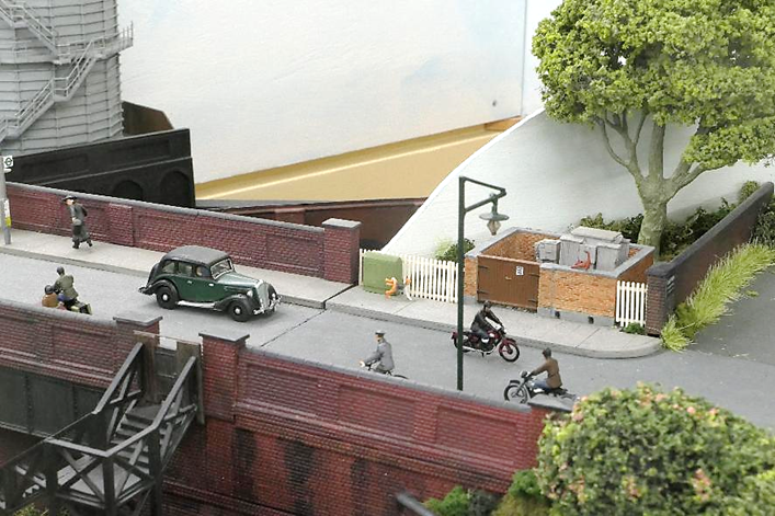 As traffic passes on Somersbury Lane, a dog cocks its leg against a telephone cabinet while a cat stretches in safety on the top on the domestic sub-station’s wall.
Both the road bridge and the curved corner board containing the Public House can each be separately removed for maintenance access.
www.EwhurstGreen.com
