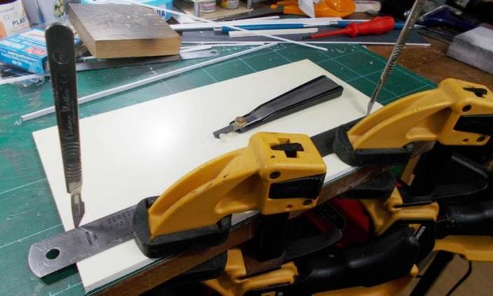 The 5mm foamboard is clamped ready for cutting into strips with the two scalpels being used to line up the straight edge. Resting behind is the Tamiya plastic scribing tool used to gradually cut through the board.
www.EwhurstGreen.com